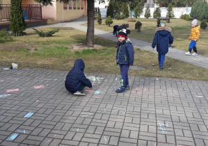 Dzieci malują kredami po chodniku
